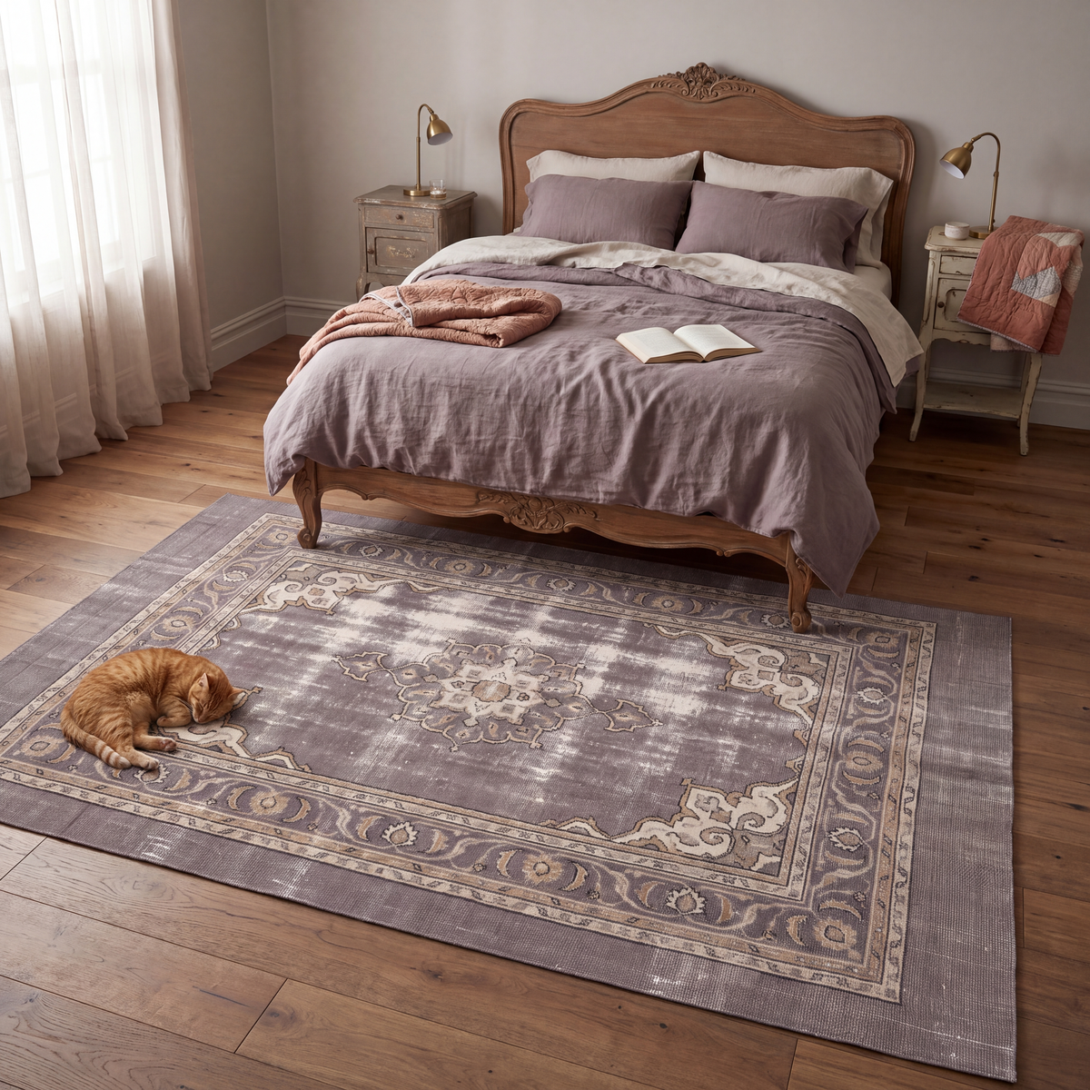 The rug at the foot of a bed with a cat asleep on it.