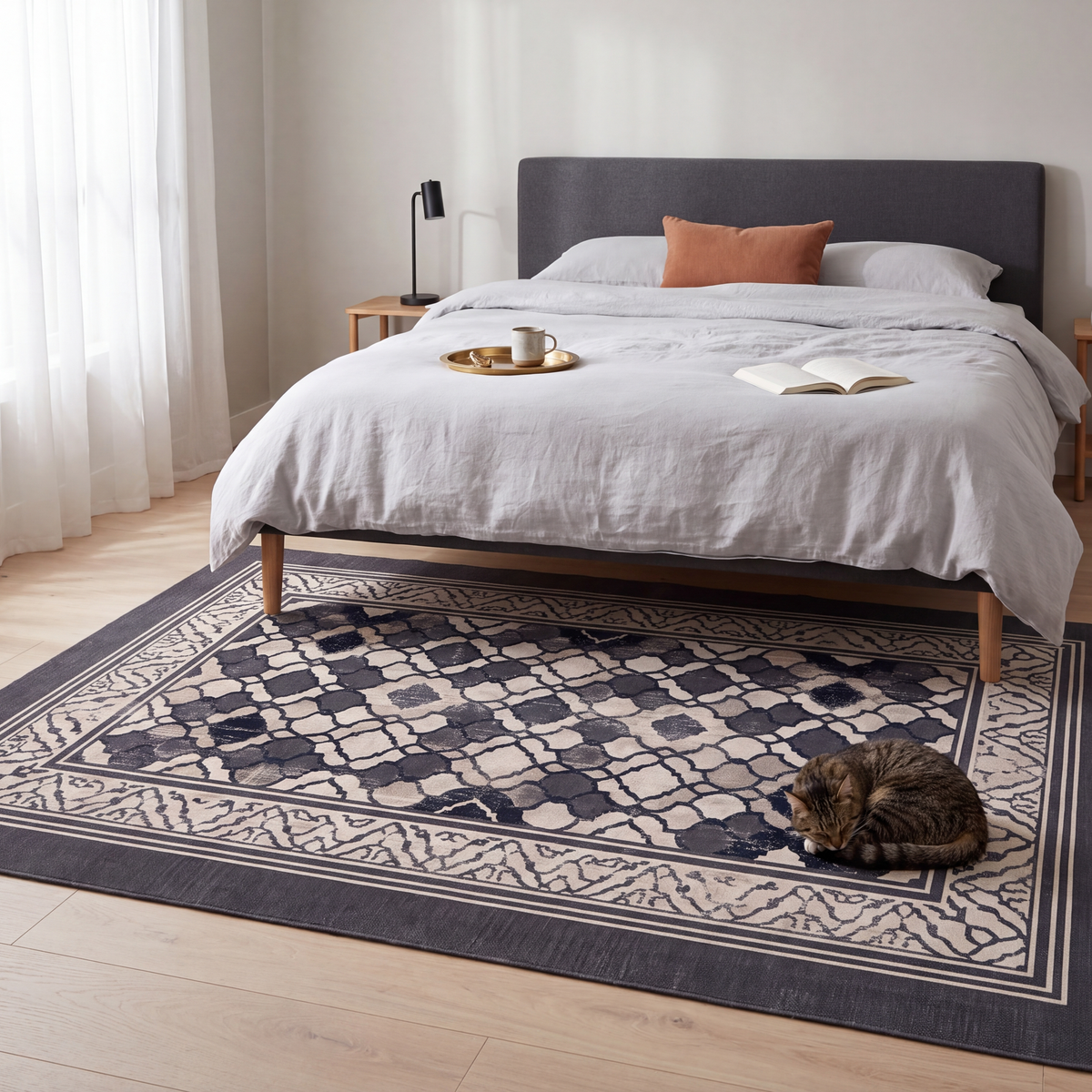 The rug at the foot of a bed with a cat asleep on it.