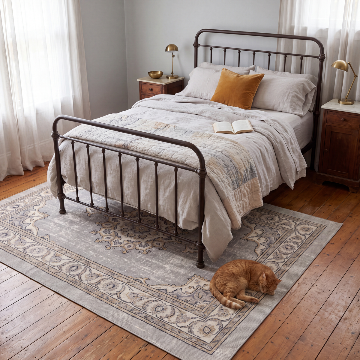 The rug at the foot of a bed with a cat asleep on it.